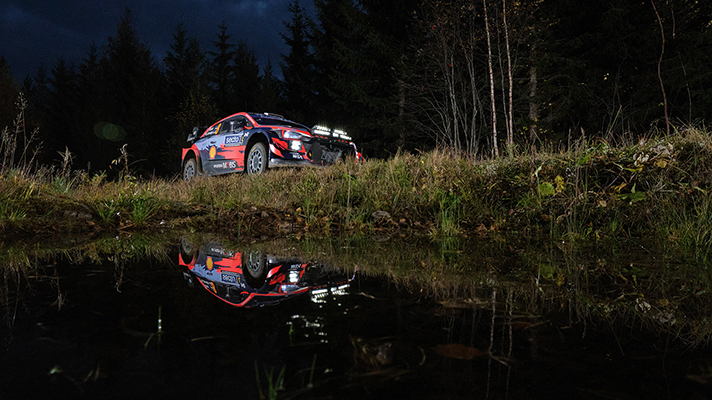 어둠이 짙게 깔린 비포장도로를 달리는 WRC car 측면