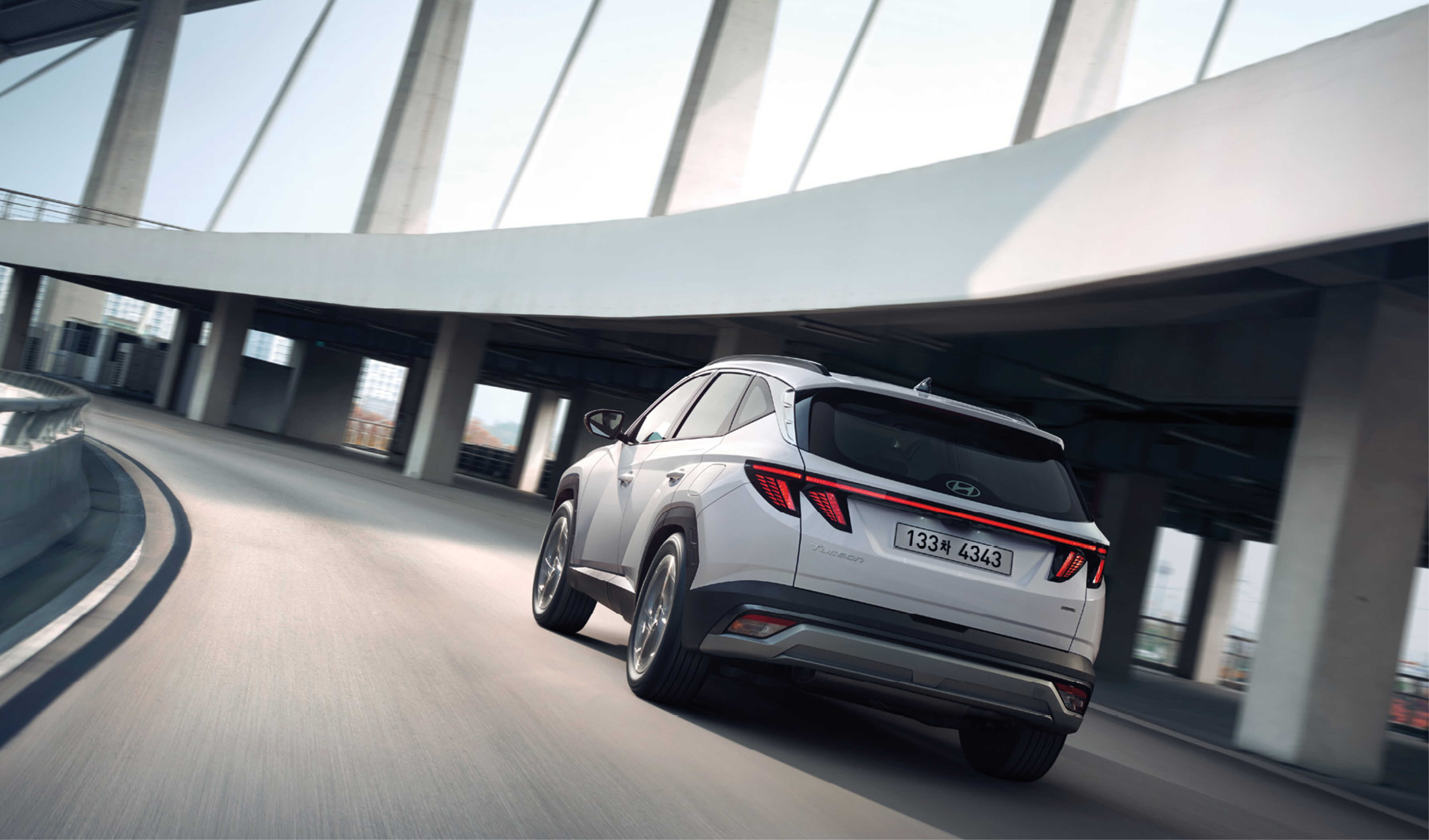 Rear view of The New Tucson driving on a curved road