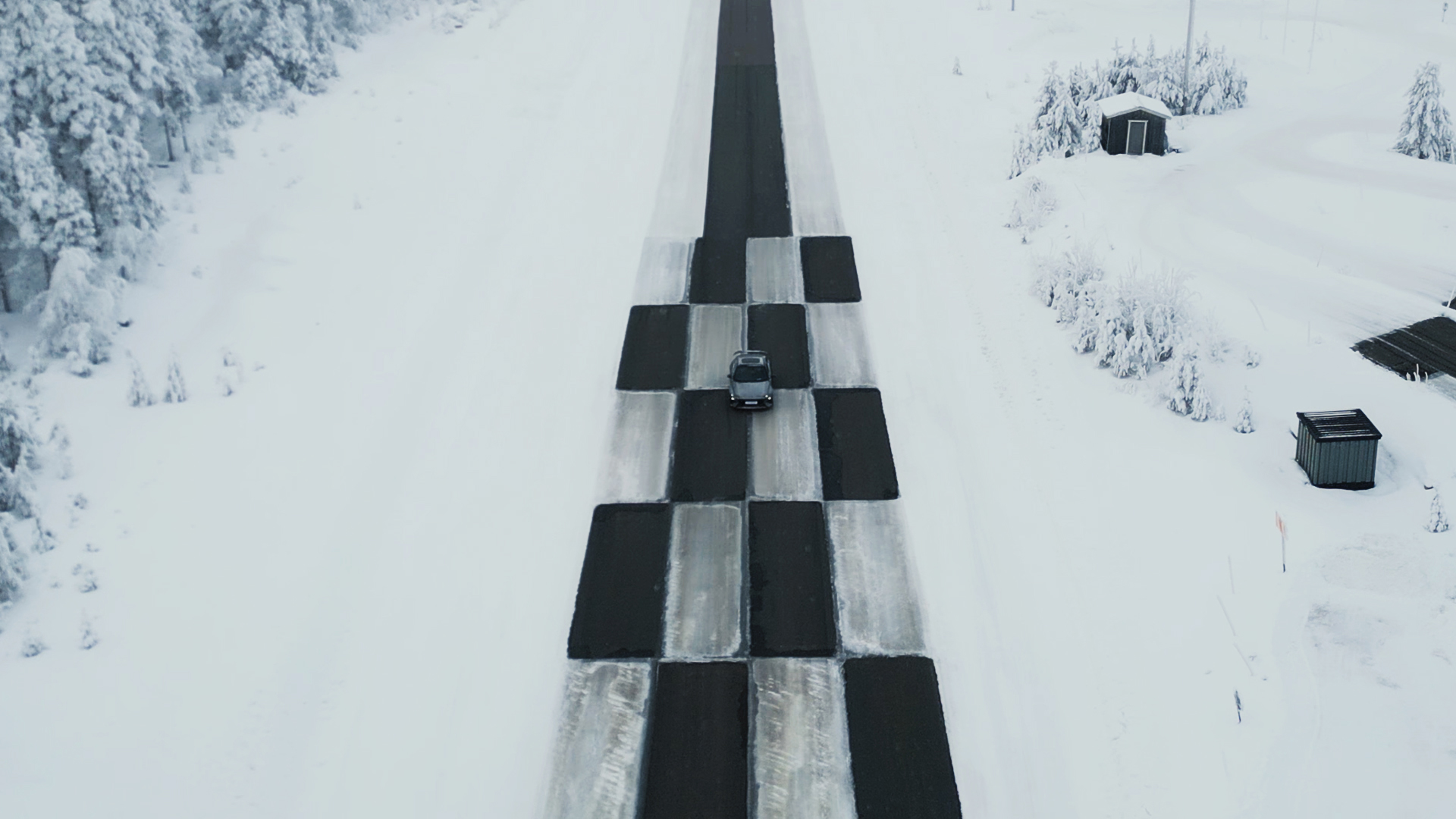 A checkered straight test track on a snowy surface for driving performance evaluation