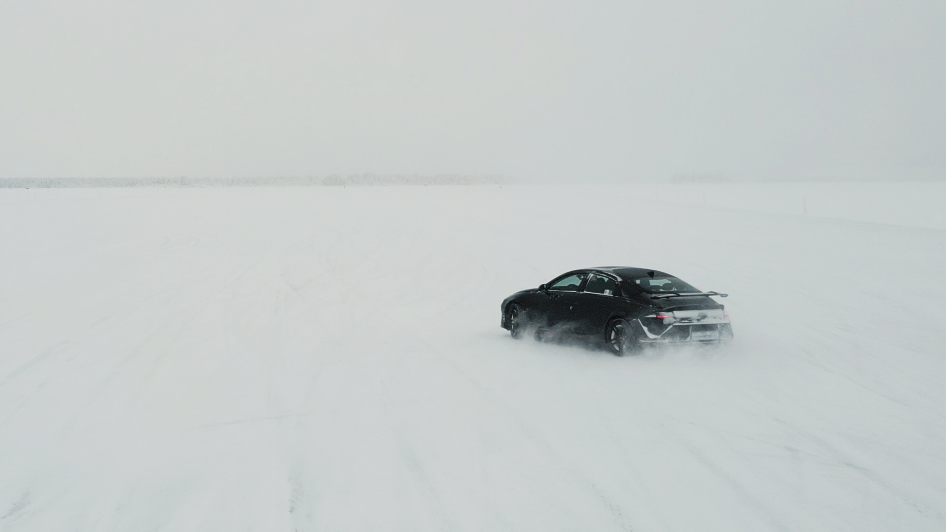 A vehicle driving alone across a vast snowy landscape