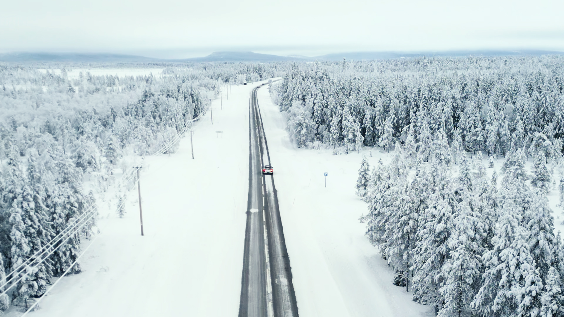 Aerial view of a test road cutting through a snow-covered forest