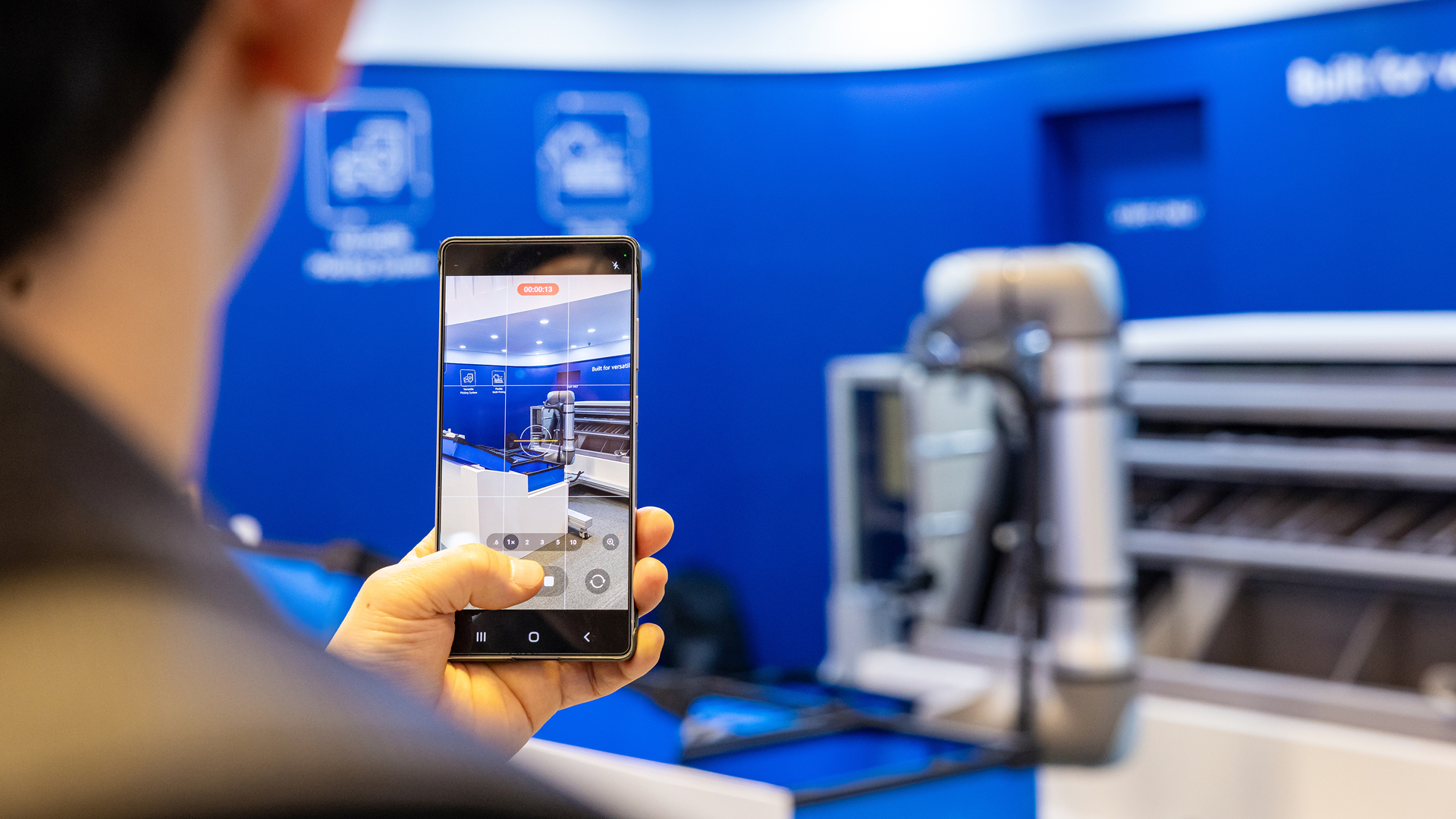 Visitor taking a photo of the Hyundai GLOVIS booth with a smartphone