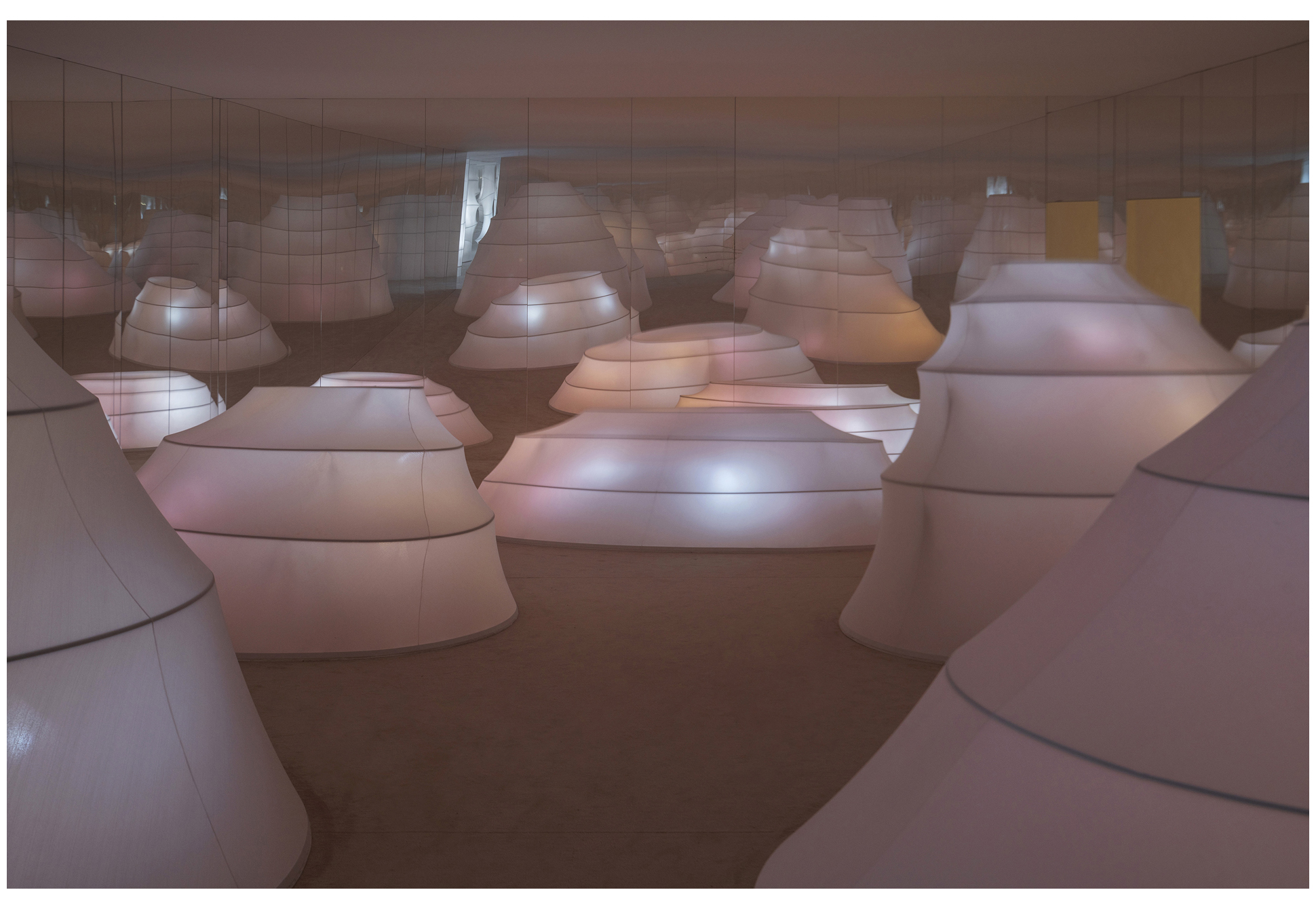 A dreamy installation art space with rounded objects arranged under pink lighting