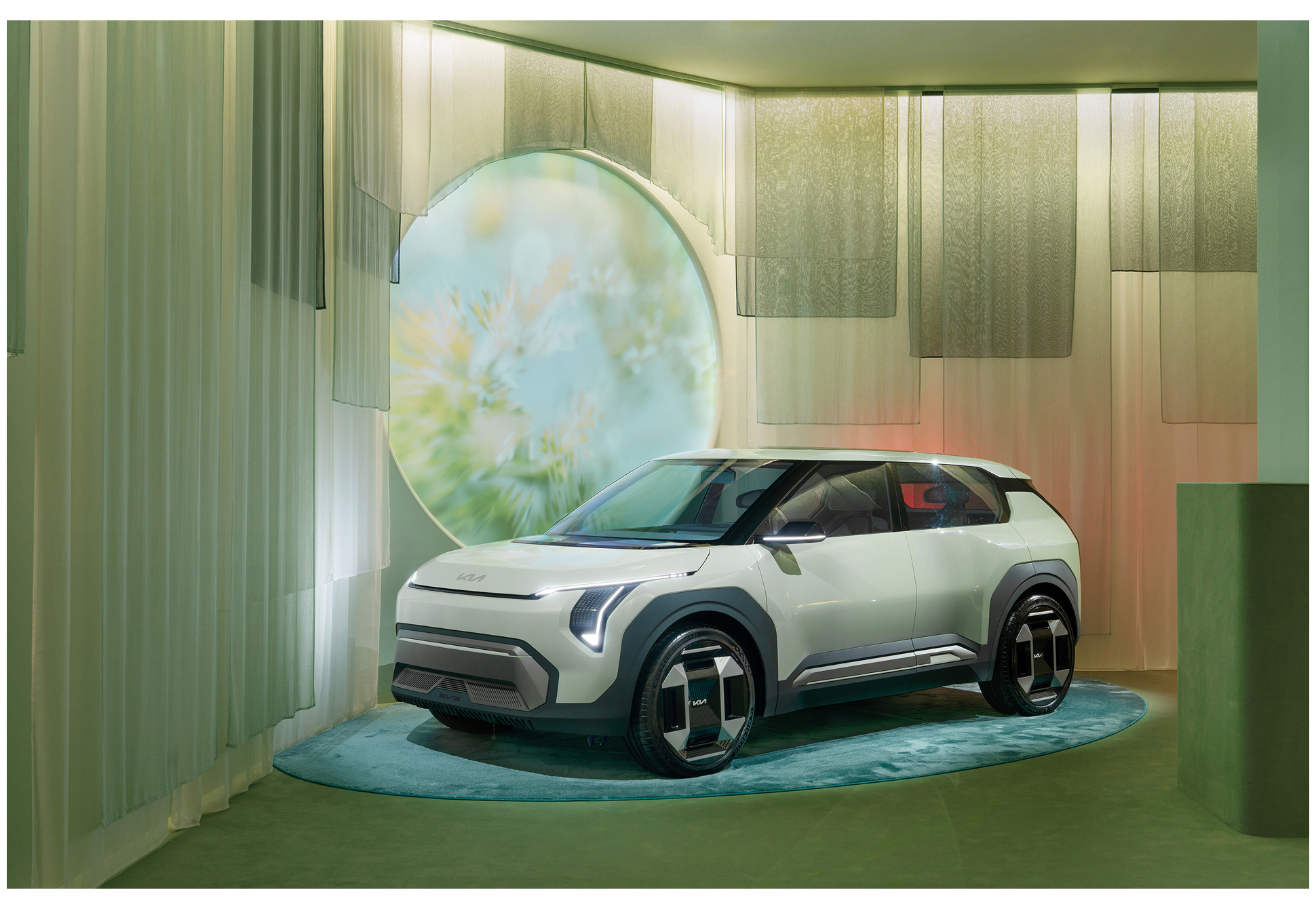 An exhibition scene with a circular digital graphic projected onto a vehicle's windshield (EV3)