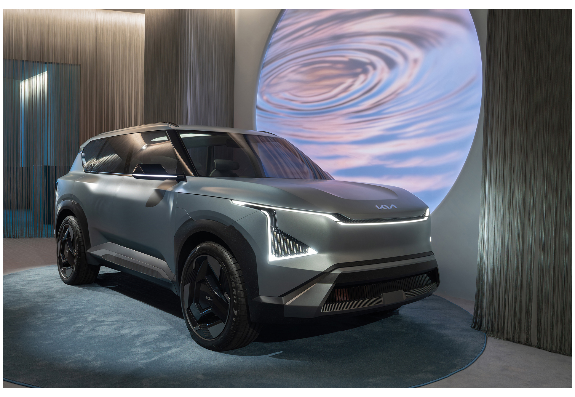 전시장 내부에 SUV 차량이 전시되고 뒤편에 원형 그래픽이 비춰진 모습(EV5)