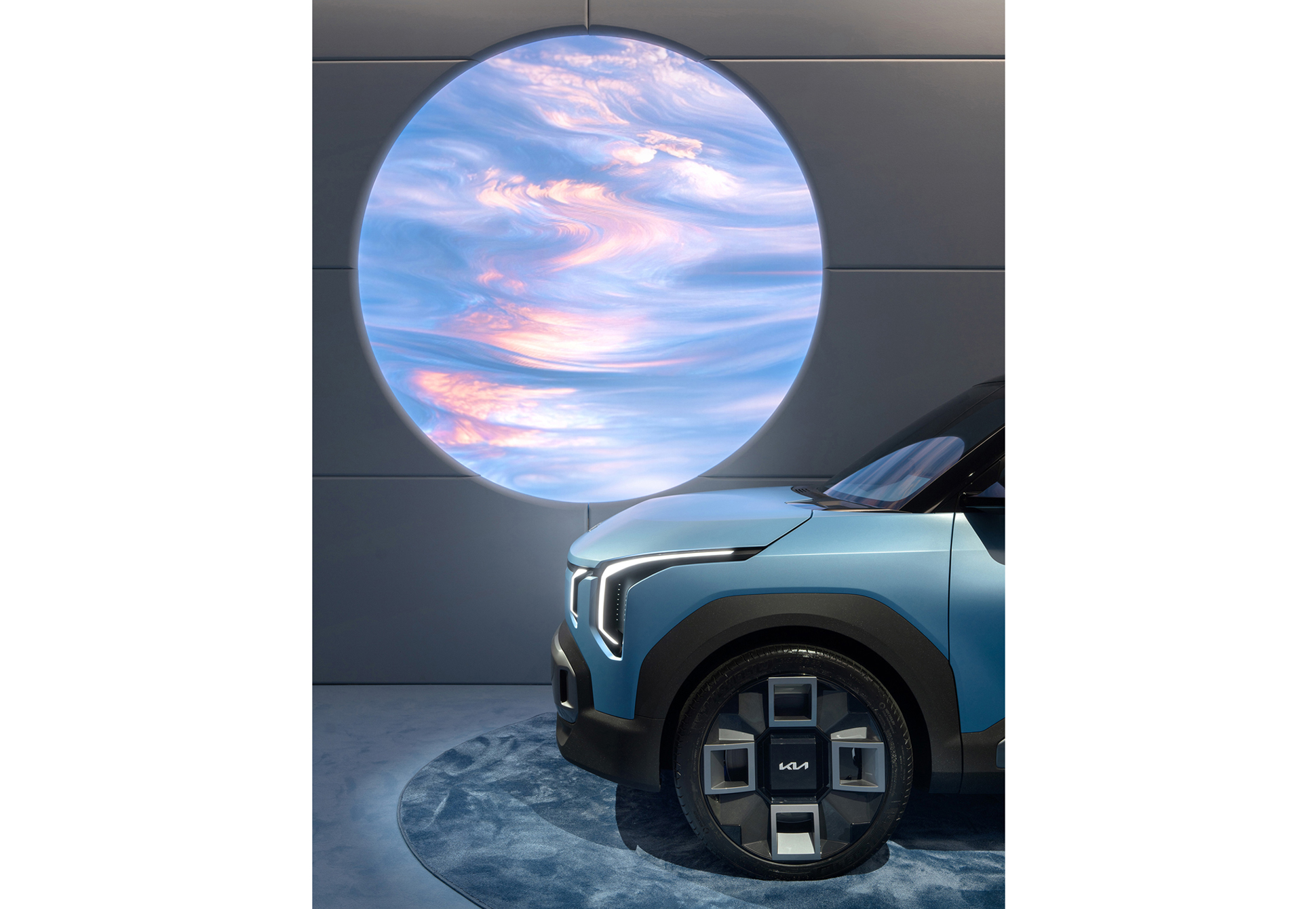 An exhibition scene with a circular digital graphic projected onto a vehicle's windshield (EV2)