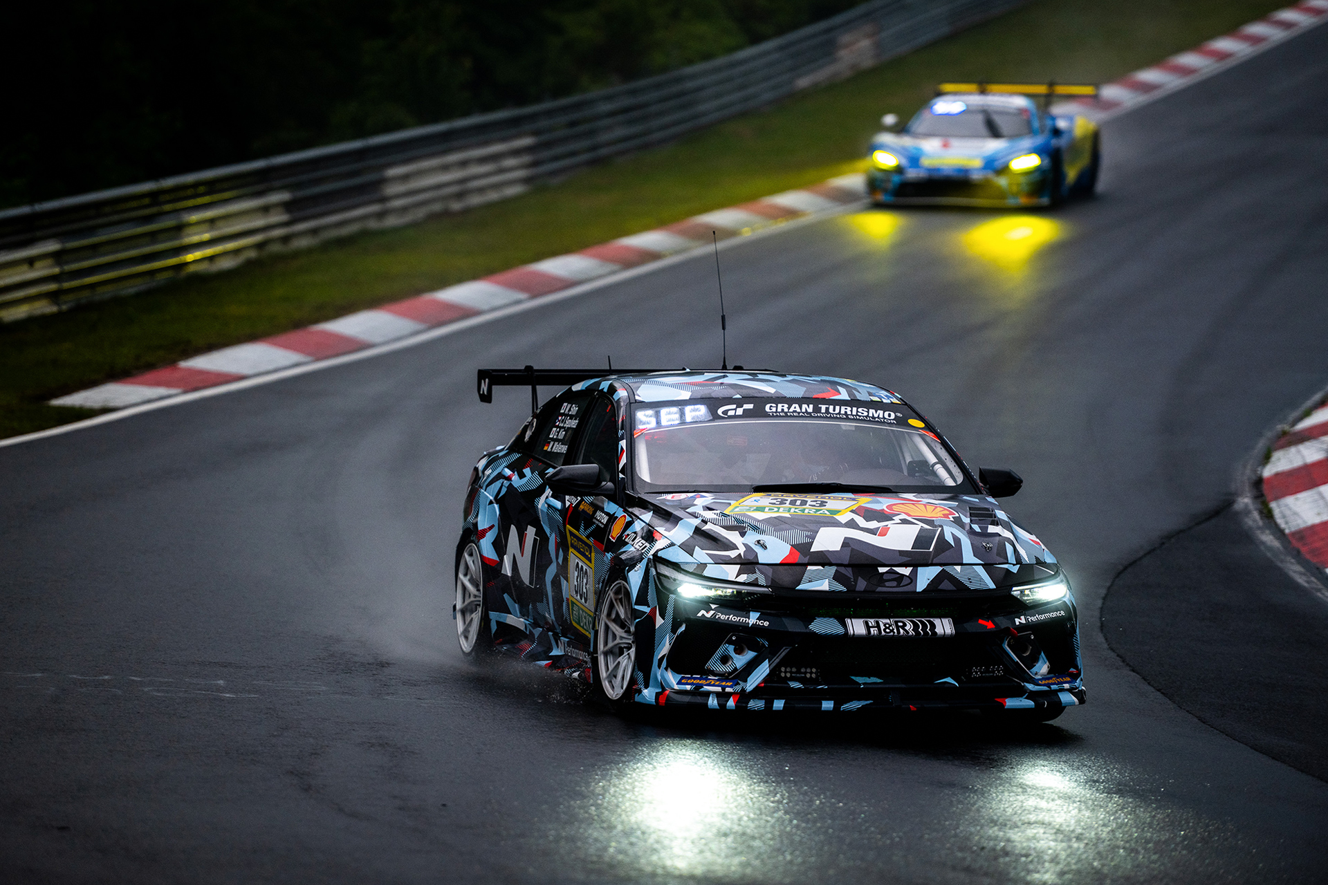 A race car driving at night on the Nürburgring circuit