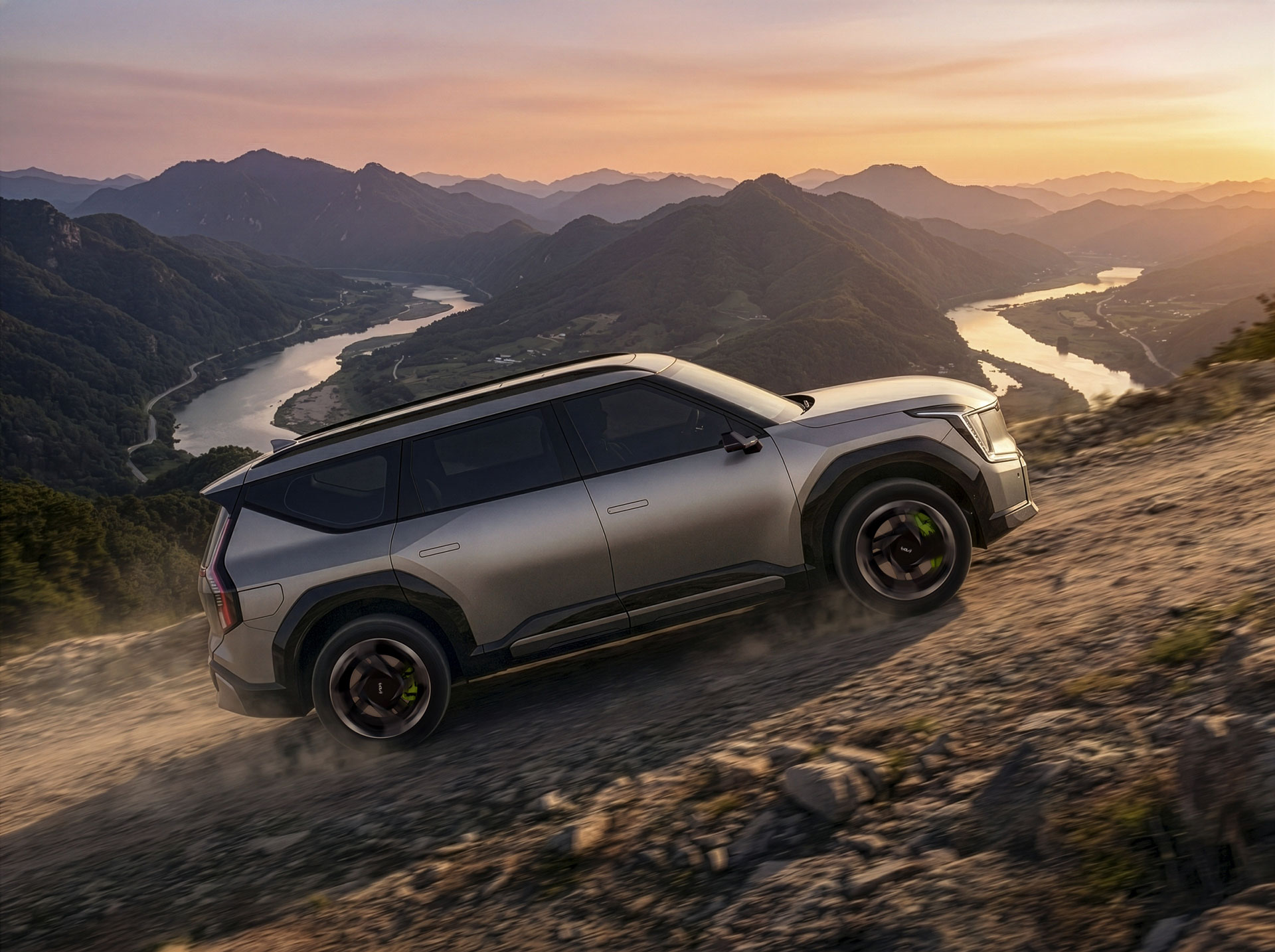 A side view of an EV9 GT climbing a rough road.