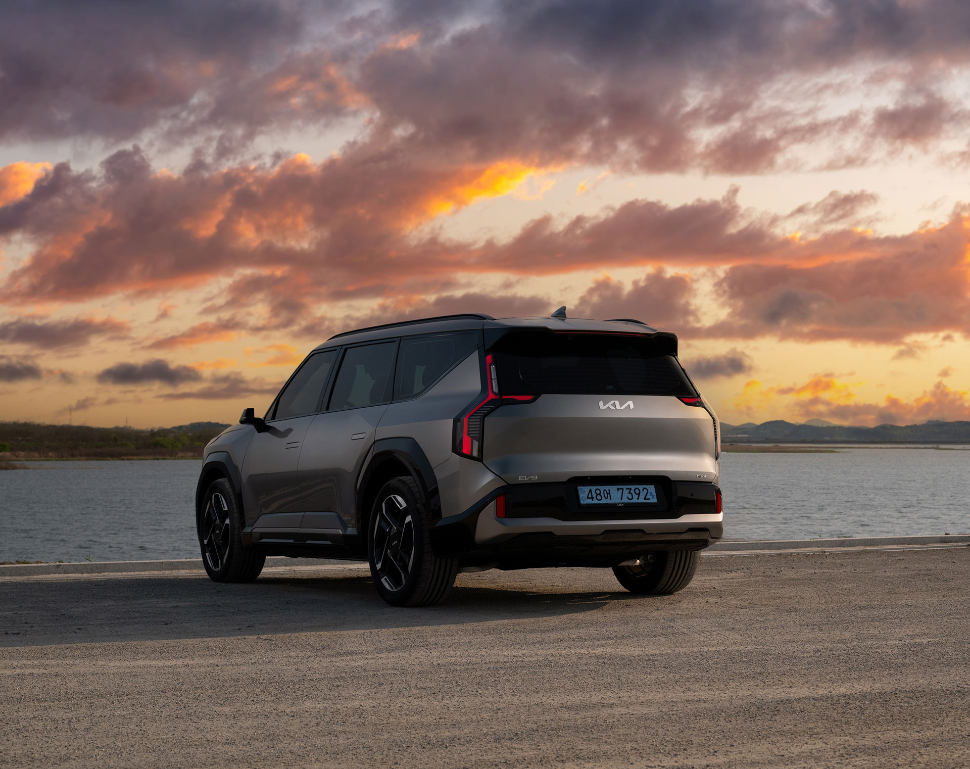 Rear three-quarter view of an EV9 GT parked by the coast.