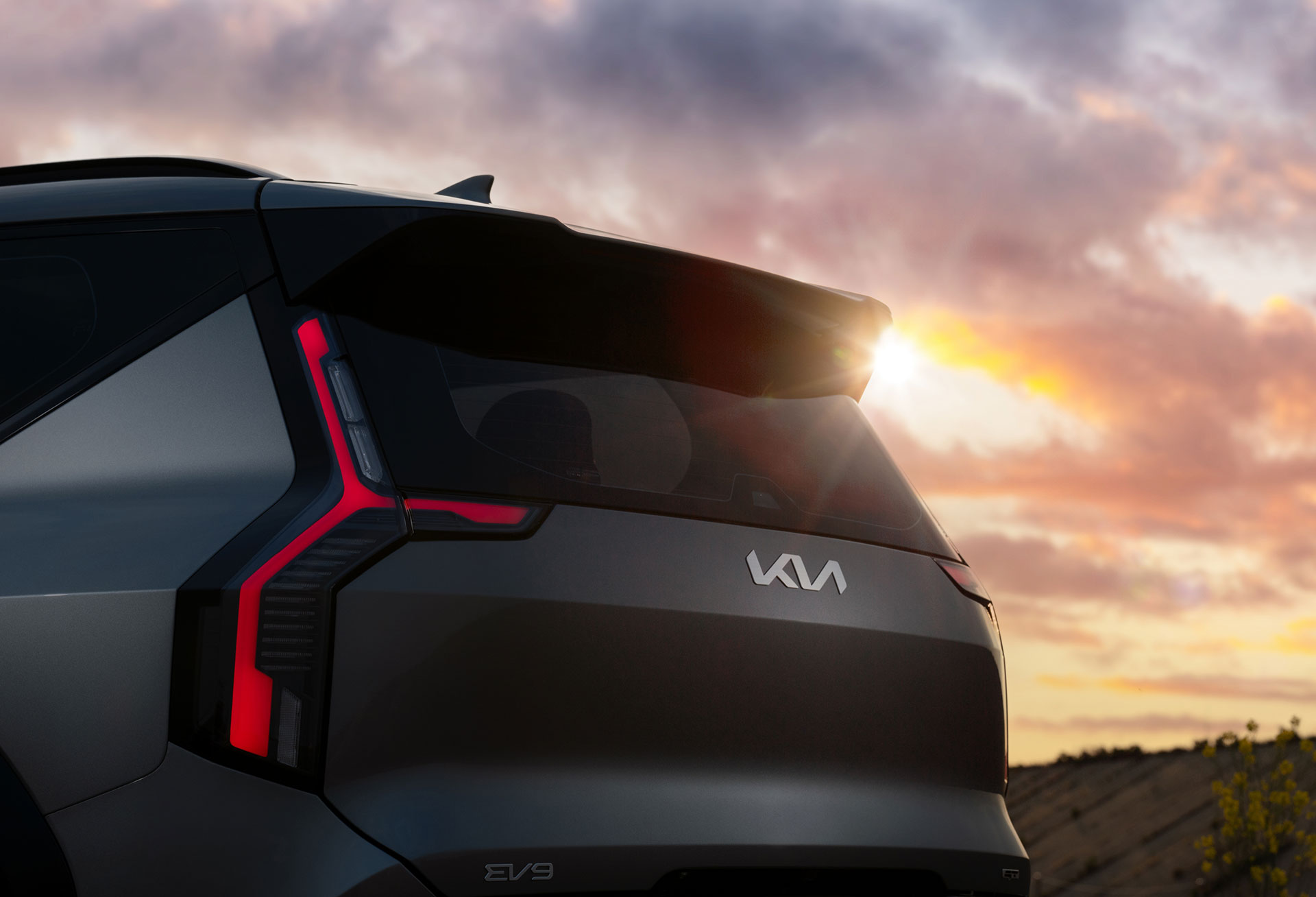 Rear three-quarter view of the EV9 GT under a sunset sky.