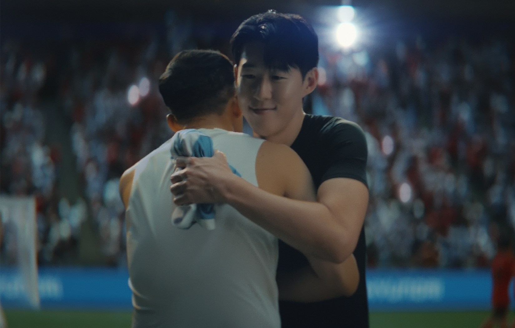 축구장에서 유소년 선수와 포옹하고 있는 손흥민 선수
