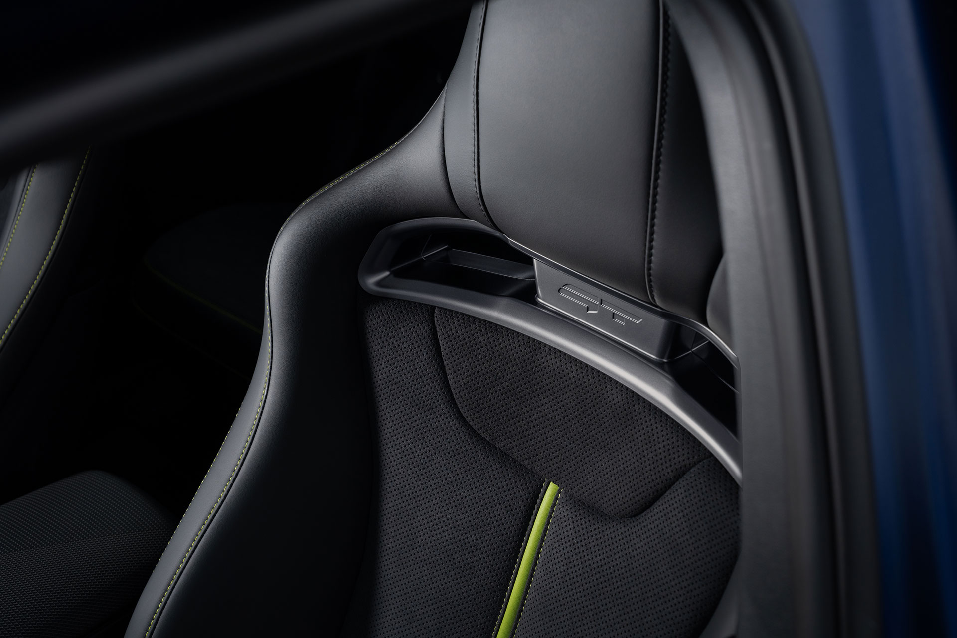 Neon-green stitching and a GT emblem on a black leather sport seat